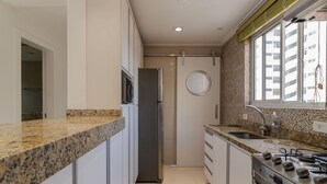 A modern kitchen with granite countertops, stainless steel appliances, and a window with a view of a building. - Ap Bela Vista c Portaria 24h Paulista e Masp (São Paulo)