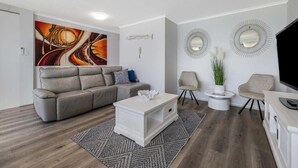 A modern living room with a sofa, coffee table, and two chairs. - Sunny Coast Escapes Maroochydore (Maroochydore)