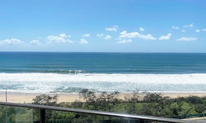A beach view with waves, a clear sky, and some trees in the foreground. - Sunny Coast Escapes Maroochydore (Maroochydore)