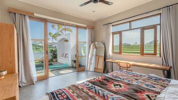 Quarto com cama, escrivaninha e vista para um campo verde.