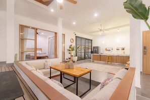 Ein modernes Wohnzimmer mit einer Couch, einem Holztisch und einer Küche im Hintergrund.