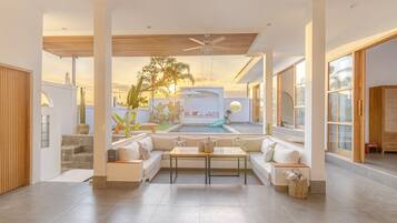 Uma sala de estar ampla com piscina, assentos confortáveis e janelas grandes.
