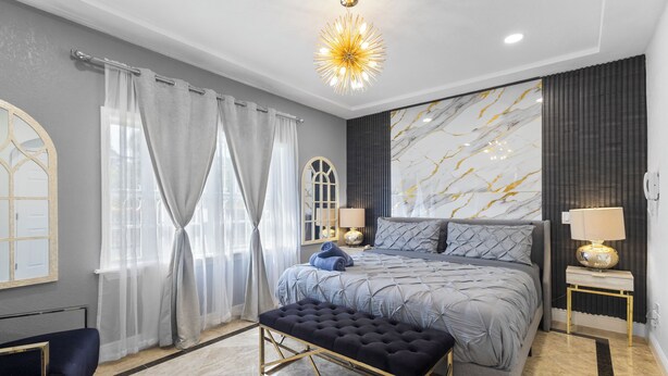 Camera da letto moderna con un letto grande, una panca, una scrivania e un lampadario.
