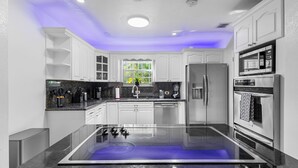 Una cucina moderna con mobili bianchi, un piano di lavoro nero, un forno integrato e una finestra vista verde.