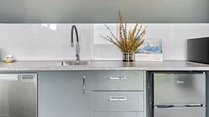 Una cocina moderna con un lavamanos de acero inoxidable, un florero con flores amarillas y un refrigerador.