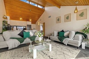 Ein modernes Wohnzimmer mit zwei Sofas, einem Couchtisch und einer Küche im Hintergrund.