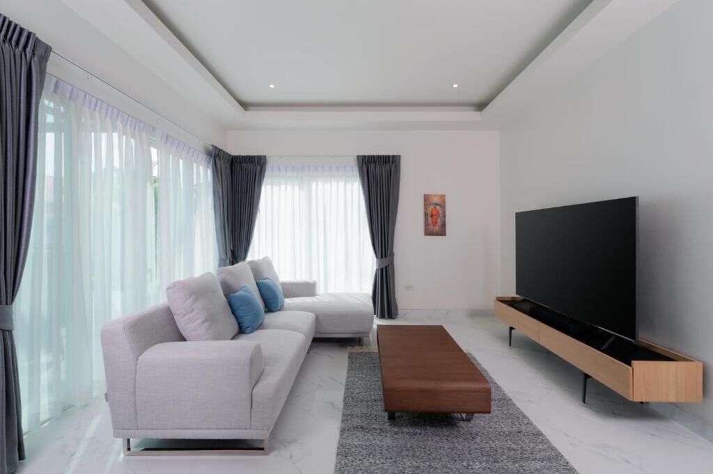 Una sala de estar moderna con un sofá, una mesa de centro, un televisor y un cuadro en la pared.