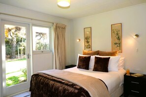Ein Schlafzimmer mit einem Bett, einem Nachttisch, einem Fenster mit Vorhängen und zwei Wandleuchten.
