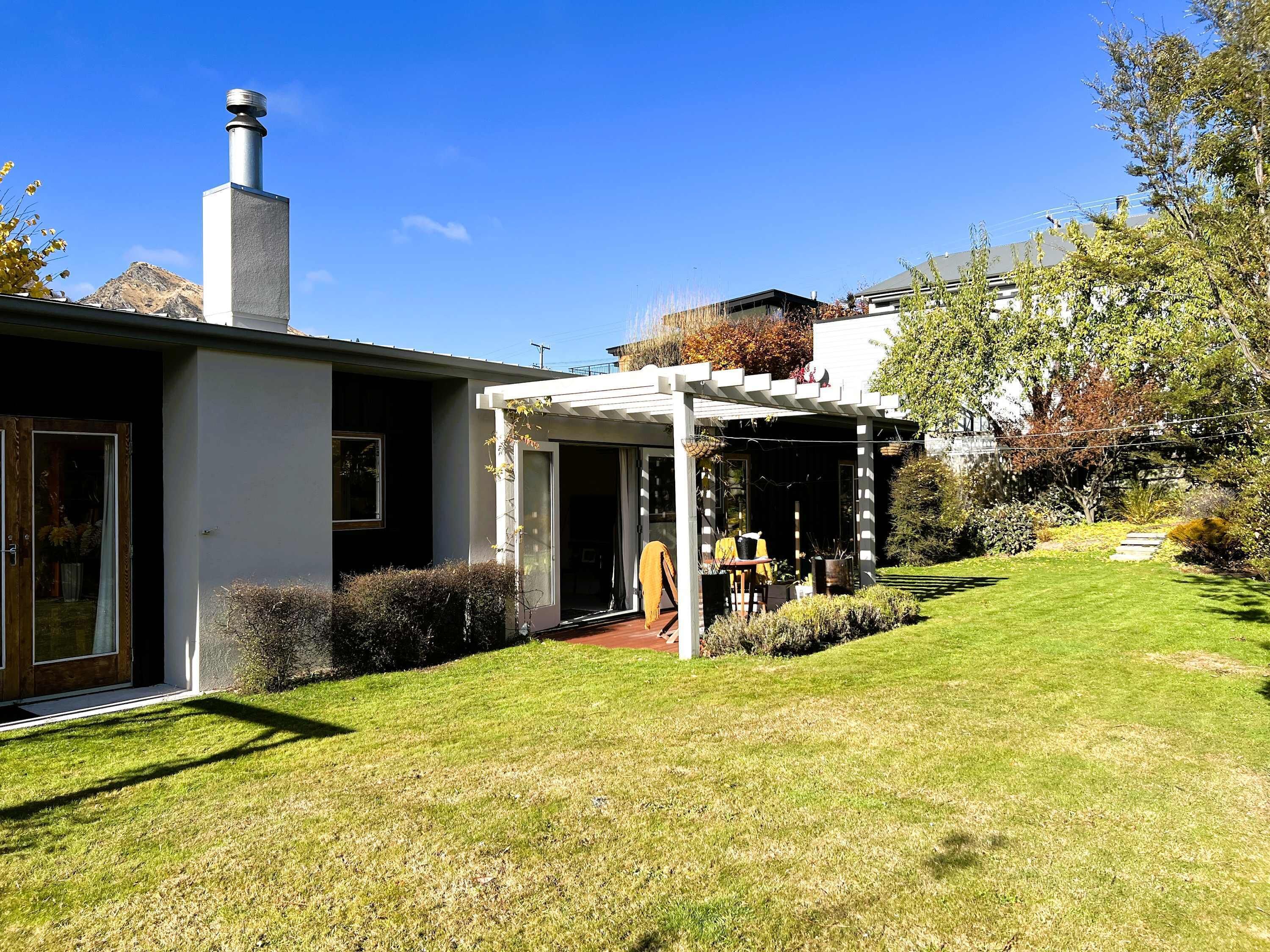 A modern house with a covered patio, a chimney, and a well-maintained lawn.