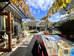 Eine Holzterrasse mit Gartenmöbeln, einem Grill und einem Tisch mit Getränken und Snacks.