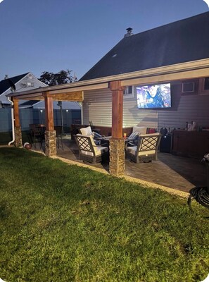 A covered patio area with outdoor furniture and a television screen. - Adorable 2-br apt Pet-Friendly .Fast WiFi .Near Airport & LIRR (Central Islip)
