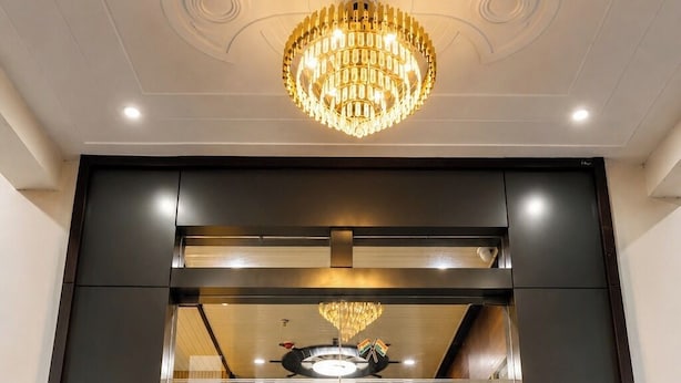 Um lobby de hotel moderno com um lustre imponente, uma recepção e uma área de estar.