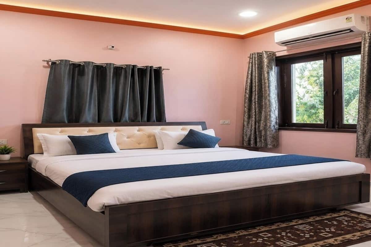 A bedroom with a bed, nightstands, a window with curtains, and an air conditioning unit.