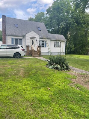 Una casa de dos pisos con un porche delantero, un garaje y un césped bien cuidado.