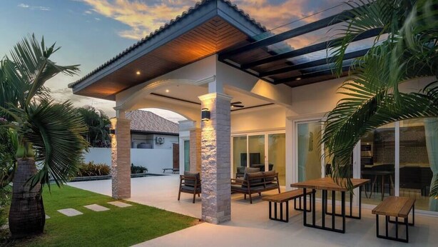 A modern house with a covered patio, outdoor seating, and a well-maintained lawn. - Orchid Paradise Homes OPV429 (Hin Lek Fai)