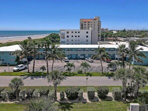Ein Hotel mit Parkplatz, Palmen und Blick auf den Strand.