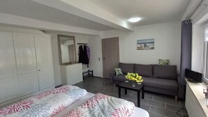 A room with a bed, a sofa, a small table with flowers, a TV, and a painting on the wall. - Vacation apartment ELBE in Relax - Belum near Otterndorf LK Cuxhaven with pool use (Belum)