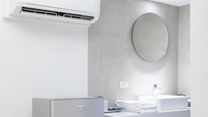 Un bagno moderno con condizionatore integrato, un lavandino con specchio e una piattaforma in legno.