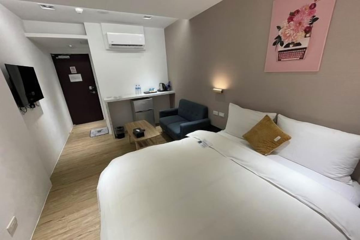 Una habitación de hotel con cama, escritorio, silla y una mesita.