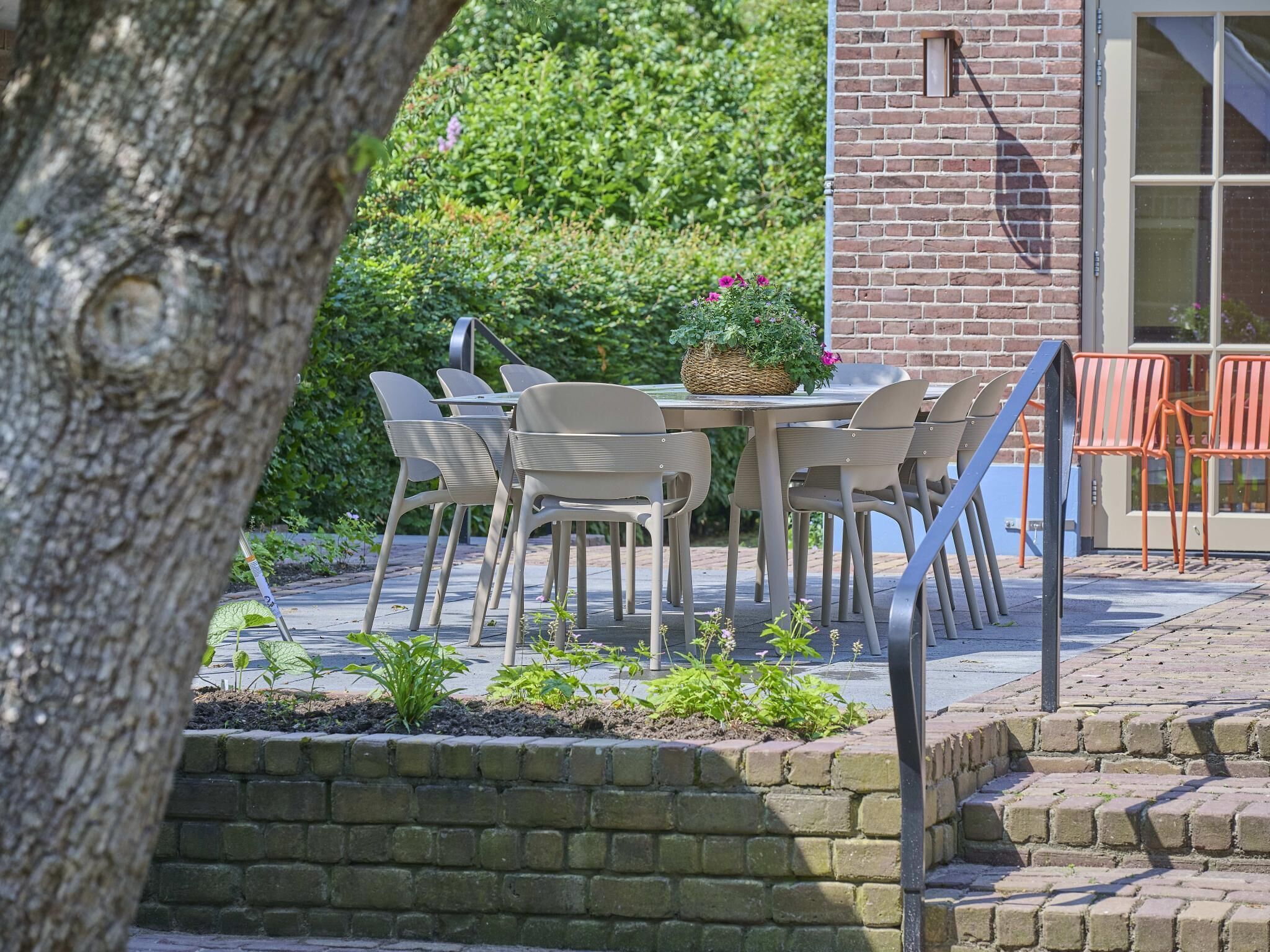 An outdoor seating area with a table and chairs, a brick wall, and a window.