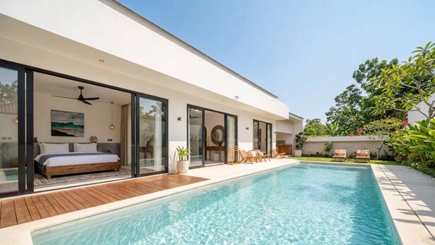 Una casa moderna amb piscina, portes corredisses de vidre i un dormitori amb llit i ventilador de sostre.