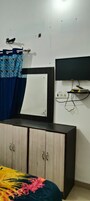 Un dormitorio con cama, armario, televisor montado en la pared y toma de corriente.