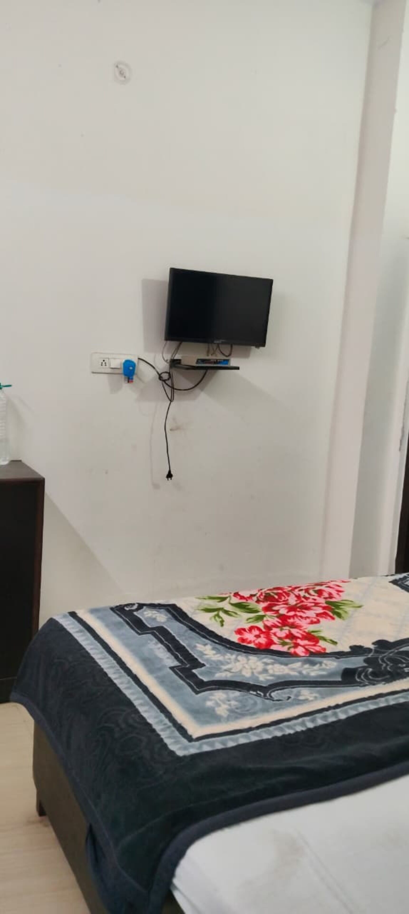 Una camera da letto con un letto, una televisione montata a parete e una presa di corrente.
