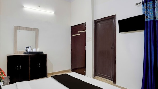 A bedroom with a bed, a dresser, a mirror, and two doors. - Yuvraj Guest House (Rudrapur)