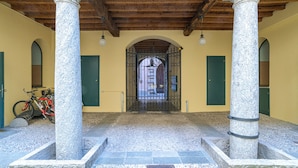 Una entrada cubierta con columnas de piedra, suelo de baldosas y una bicicleta aparcada a un lado.