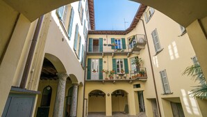 Un patio con un edificio que tiene varios balcones, columnas y un cielo azul despejado.