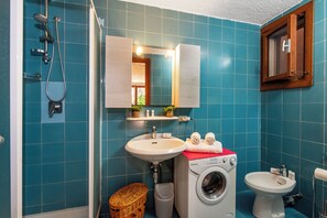 A bathroom with a washing machine, a sink, a bidet, and a shower. - Ladunia 2 (Olbia)