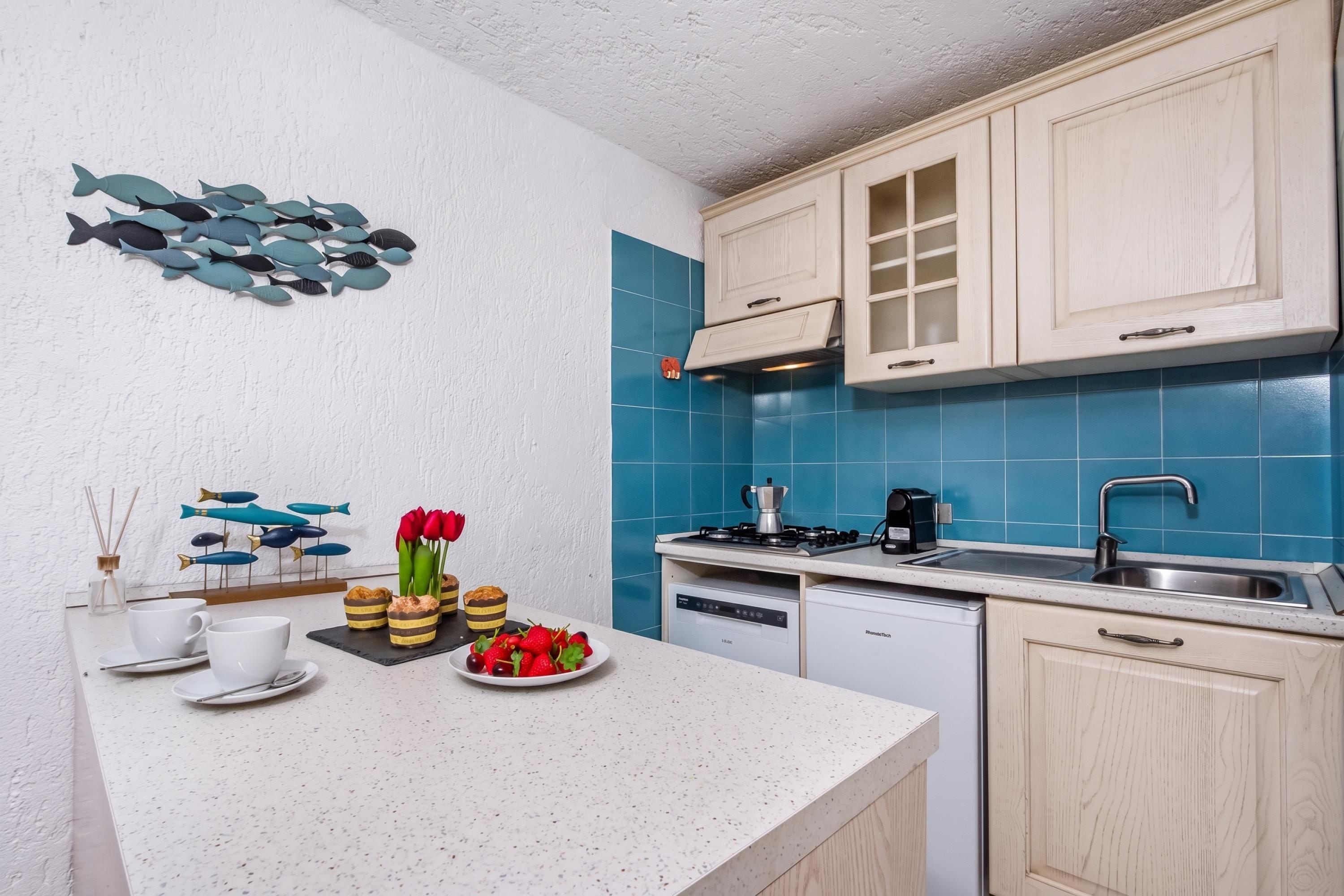 A modern kitchen with white cabinetry, blue tiles, a gas stove, and a dishwasher.