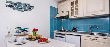 A modern kitchen with white cabinetry, blue tiles, a gas stove, and a dishwasher.