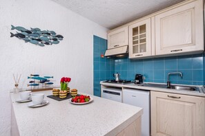 A modern kitchen with white cabinetry, blue tiles, a gas stove, and a dishwasher. - Ladunia 2 (Olbia)