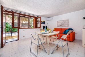 A modern living space with a dining area, a sofa, and a large window. - Ladunia 2 (Olbia)