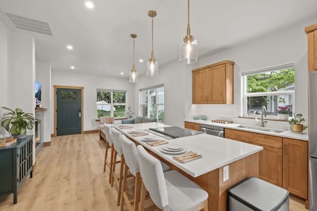 A modern kitchen with a central island, wooden cabinets, and pendant lighting.. The Parkside Porch House