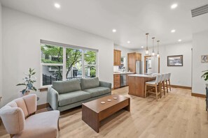 A modern living room with a sofa, coffee table, and dining area with chairs.