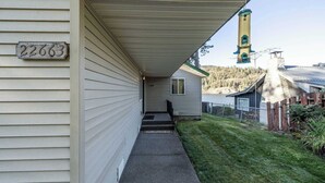 Uma casa com varanda coberta, caixa de correio e vista para uma montanha.