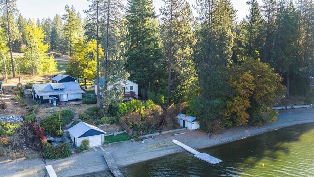 Uma propriedade à beira do lago com cabanas, um cais e floresta densa.