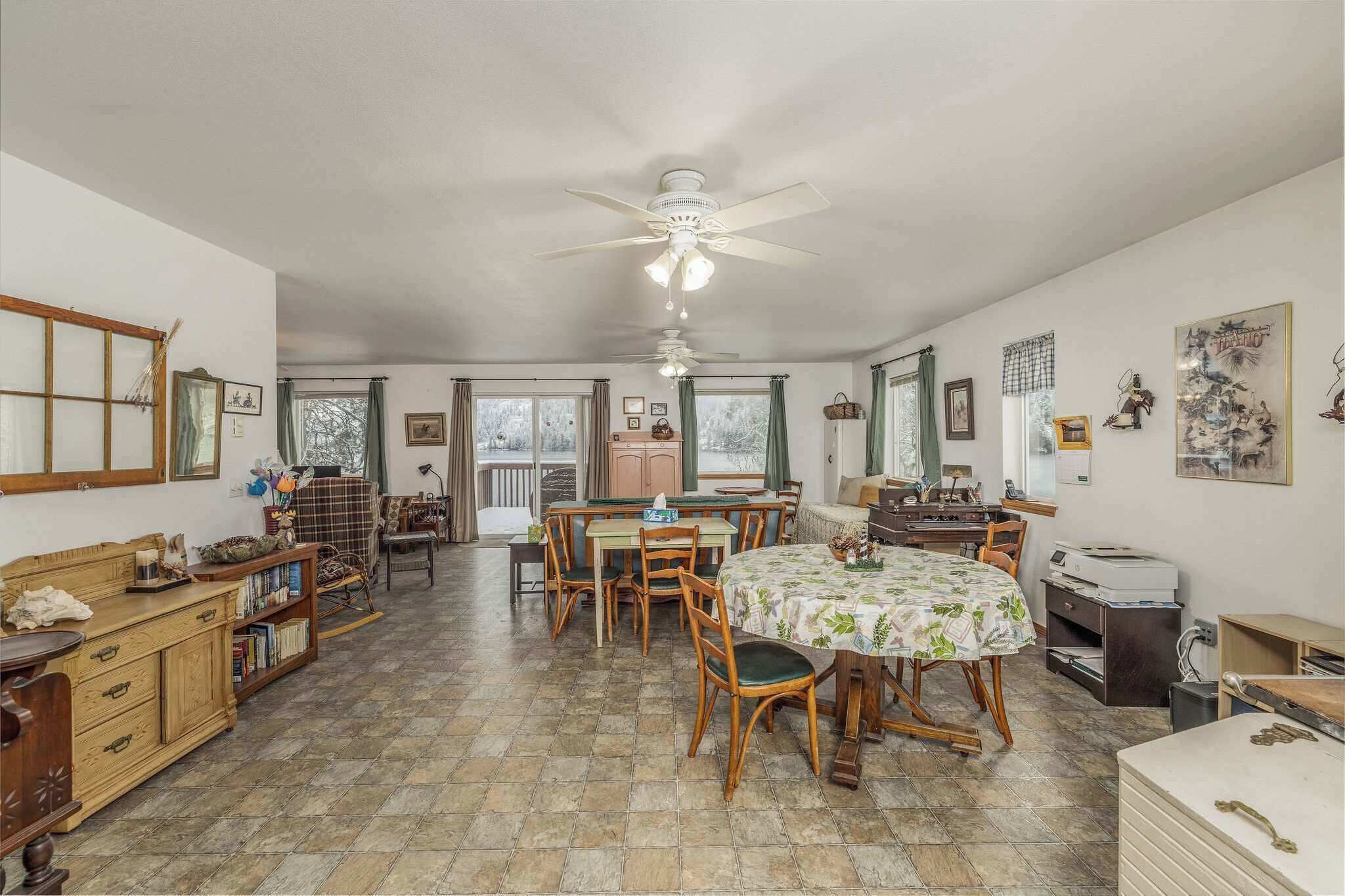 A spacious dining area with a large table, chairs, and a ceiling fan.