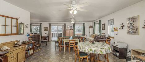 A spacious dining area with a large table, chairs, and a ceiling fan.