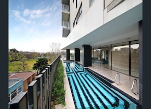 A modern building with a swimming pool, large windows, and a view of the surrounding area. - Poolside 2-Bed Apartment in South Yarra (South Yarra)