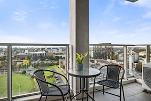 A balcony with two chairs, a table, and a potted plant. - Poolside 2-Bed Apartment in South Yarra (South Yarra)