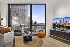 A modern living room with a large window, a flat-screen TV, and a sofa. - High-Rise 2-Bed Stay at Queensbridge (Southbank)