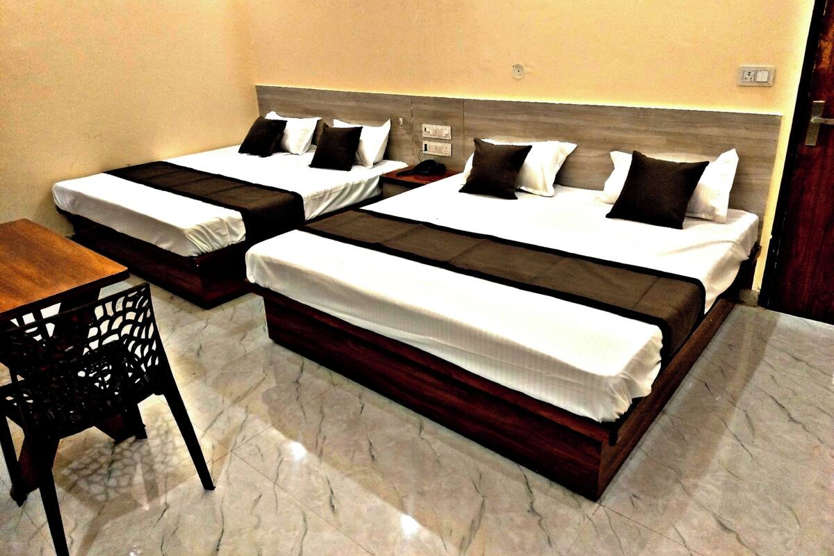 A hotel room with two beds, a wooden table, and a chair.