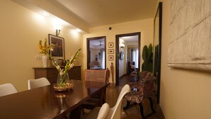 Un coin repas avec une table en bois, des chaises blanches, un vase de fleurs et une chaise à motifs.