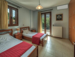 A bedroom with two beds, a radiator, a window with curtains, a ceiling light, and a framed picture on the wall. - Hidden Gem in Crete — Totally Private Villa for up to 9 Guests (Rethymno)