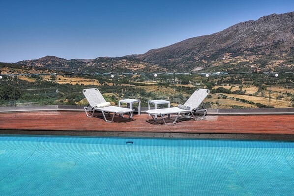 A pool with two lounge chairs and a small table, overlooking a mountainous landscape. - Hidden Gem in Crete — Totally Private Villa for up to 9 Guests (Rethymno)