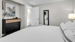 Un dormitori modern amb un llit gran, una petarrera amb mirall i un quadre penjat a la paret.