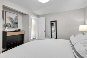 Un dormitorio con cama, cómoda, espejo y puerta.